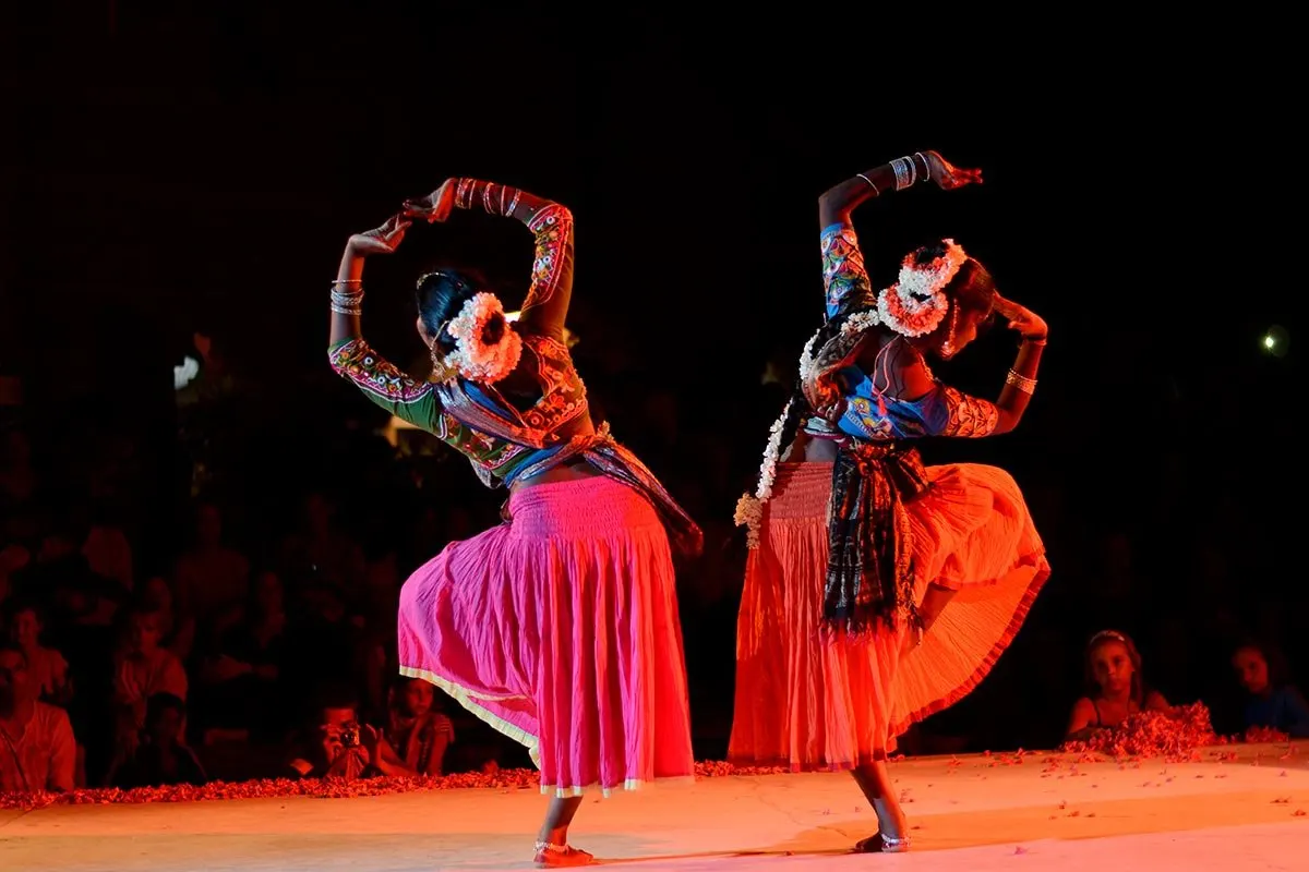 Two dancers in colourful costumes perform on stage