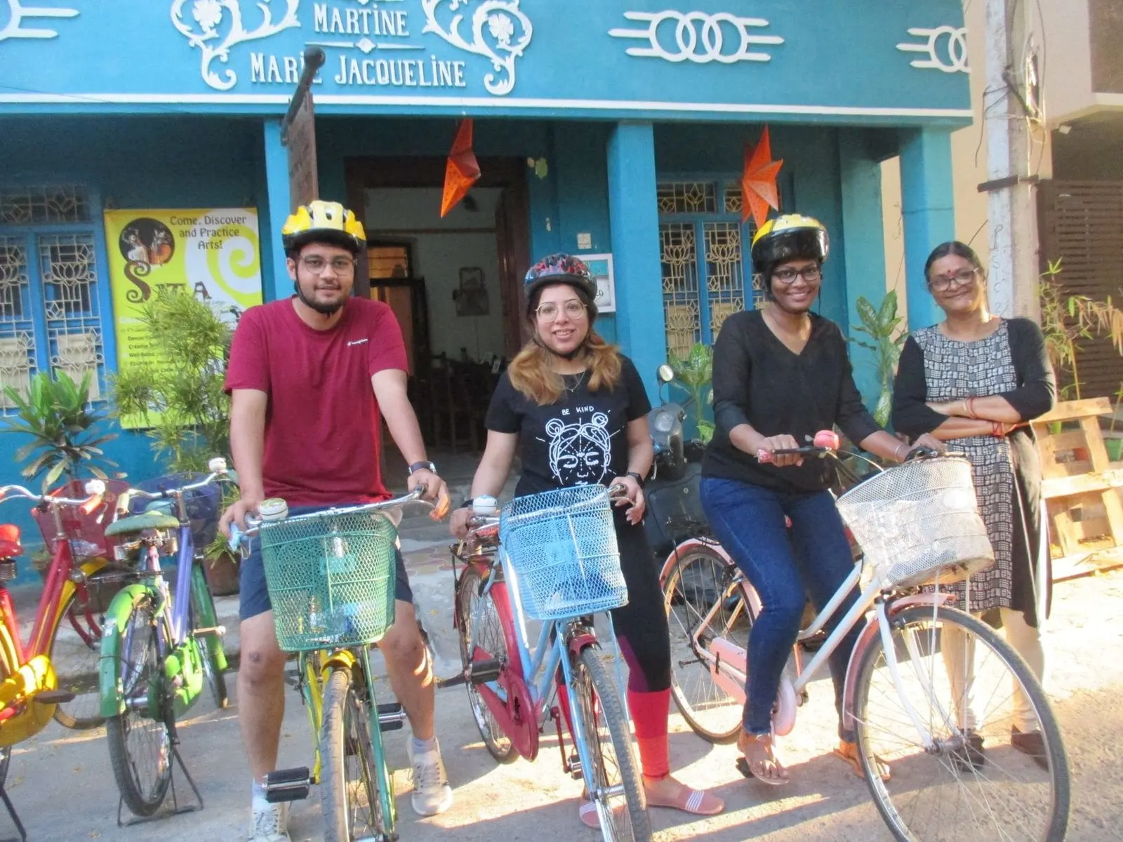 Three cyclists in helmets and a Sita team member in front of the blue Sita villa